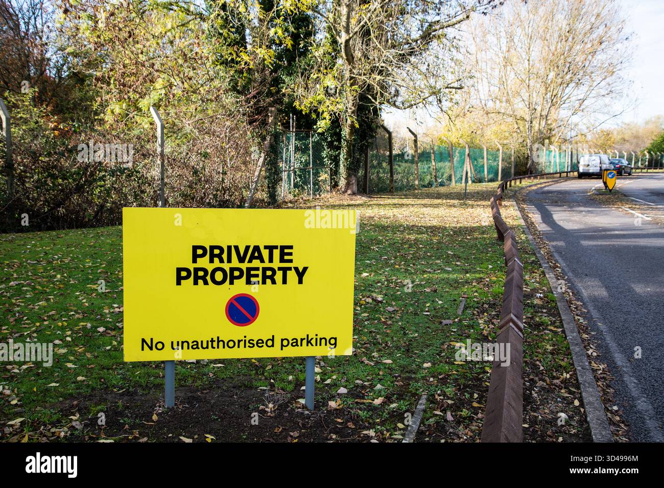 Panneau jaune « Private Property – No Unlimited parking » près d’une route verdoyante en Angleterre, symbolisant la restriction et l’accès privé à la terre. Banque D'Images