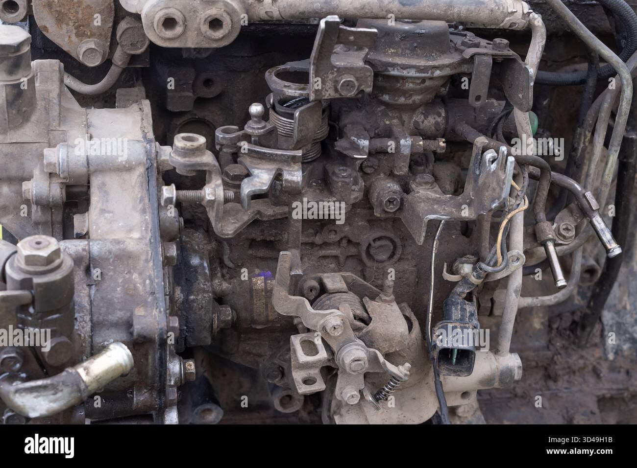 Vue rapprochée d'un moteur de voiture usé avec tuyaux, courroies et boulons visibles. Concept de réparation automobile, et maintenance industrielle. Banque D'Images