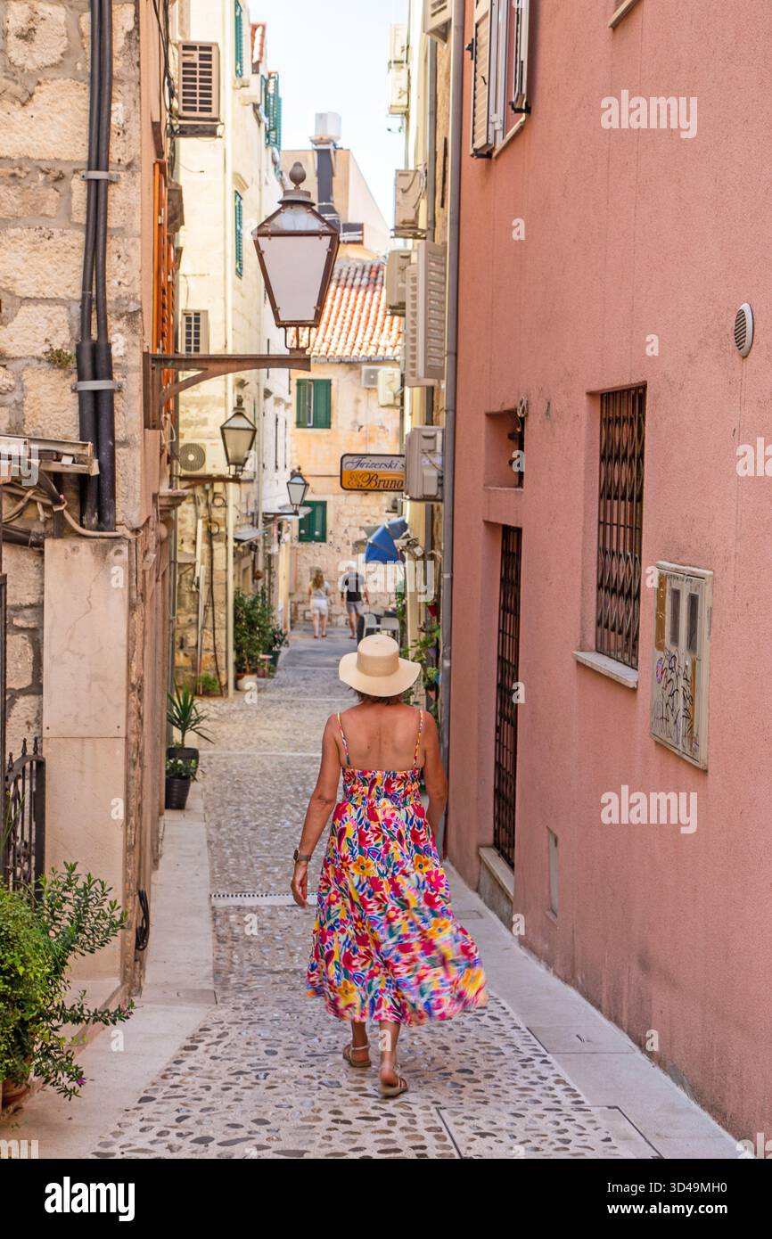 Femme touriste vacancier visitant la promenade à travers la jolie vieille rue pavée arrière dans la ville croate de Makarska Croatie Banque D'Images