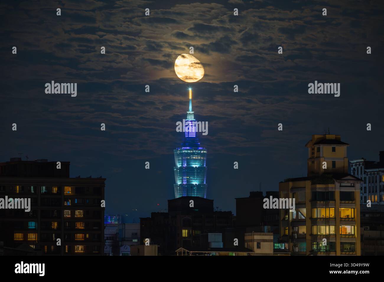 New Taipei City, Taiwan - 15 juin 2025 : une lune se lève de façon spectaculaire derrière le gratte-ciel illuminé Taipei 101 la nuit. Fenêtres éclairées de l'appartement Ar Banque D'Images