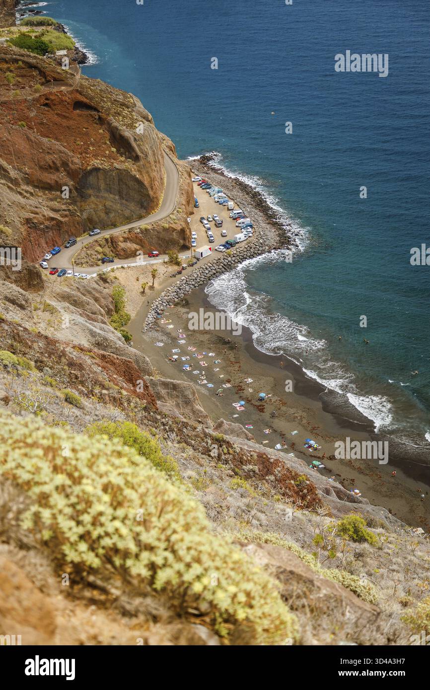 La beauté sauvage de Playa de las Gaviotas, avec une route escarpée descendant vers le sable sombre de la plage et l'océan, souligne le charme pittoresque de Tenerife Banque D'Images