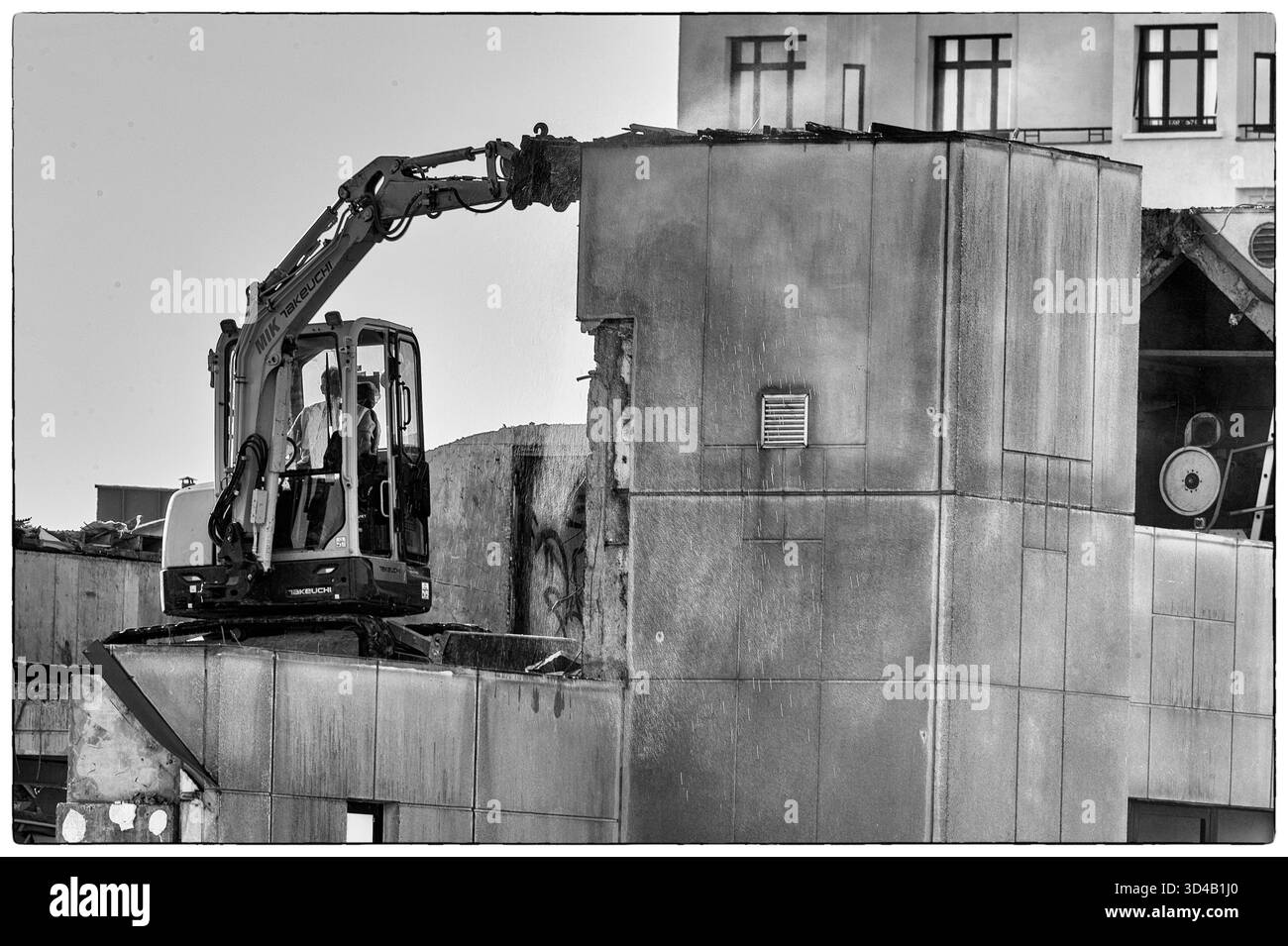 Bulldozer au travail sur le toit d'un bâtiment en cours de démolition - de l'eau est pulvérisée pour empêcher la poussière de béton de se disperser.| bulldozer au travail sur le Banque D'Images