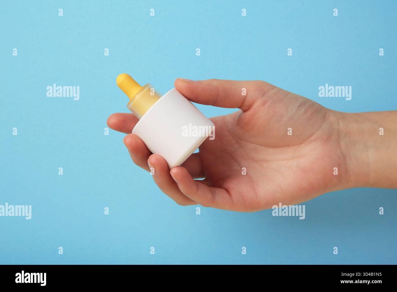 Huile cosmétique de soin de la peau de beauté dans la bouteille sur fond bleu. Maquette élégante pour les présentations de soin de la peau, de sérum ou de marque beauté. Vue de dessus Banque D'Images