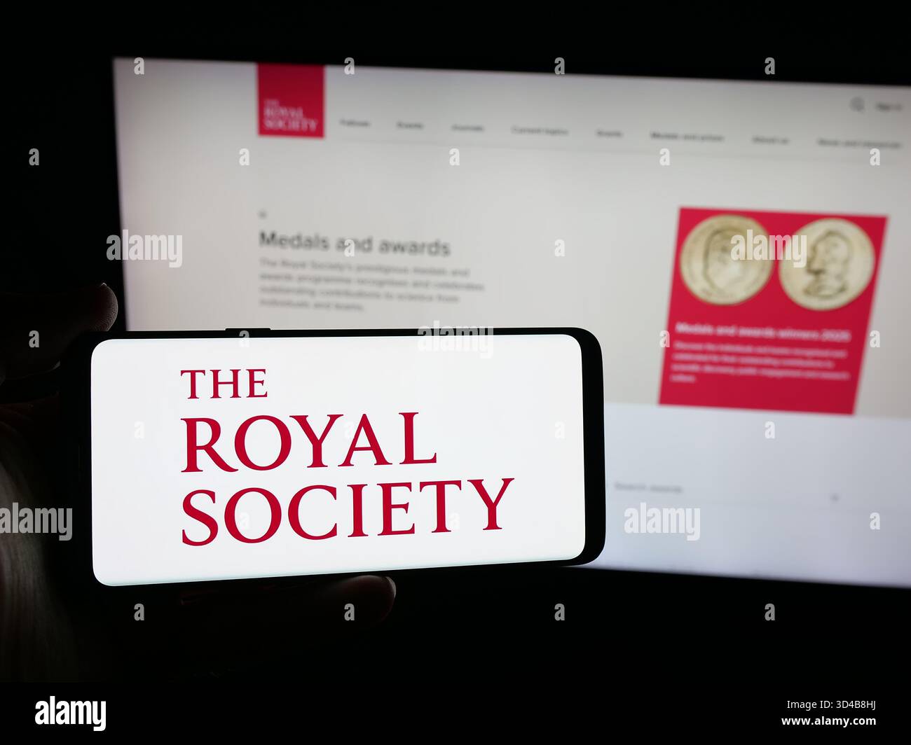 Stuttgart, Allemagne - 11-01-2025 : personne tenant un smartphone avec le logo de l'organisation britannique Royal Society sur l'écran devant le site Web. Banque D'Images