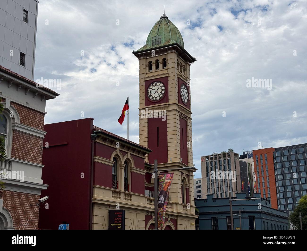 Redfern Post Office, un monument historique à Redfern, Sydney, Australie, avec sa tour de l'horloge avec un dôme vert. Le drapeau aborigène FLI Banque D'Images