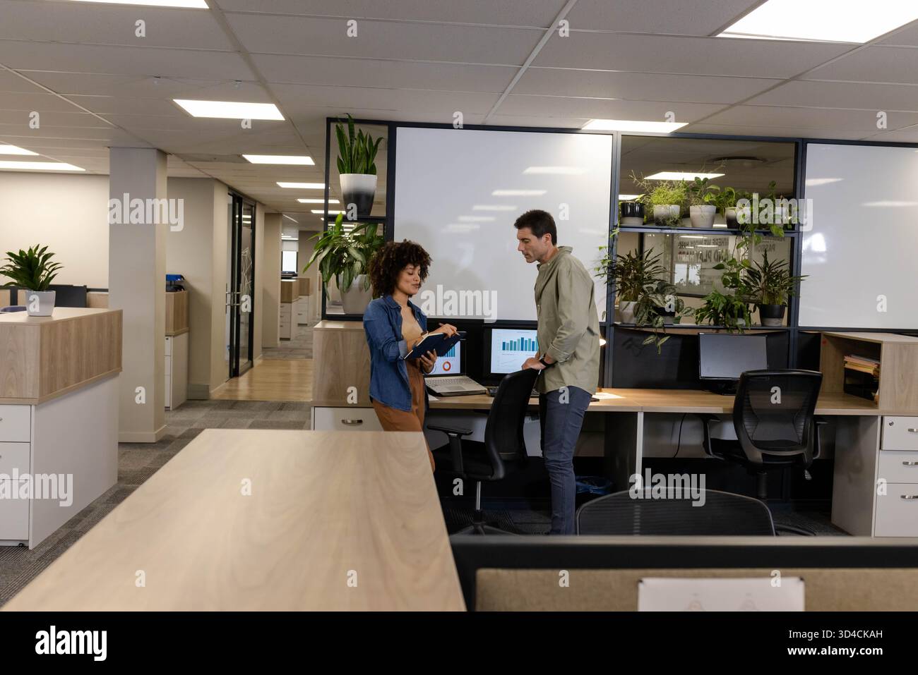 Discuter des objectifs du projet divers collègues se réunissent dans un bureau ouvert, avec tablette et tableau blanc Banque D'Images