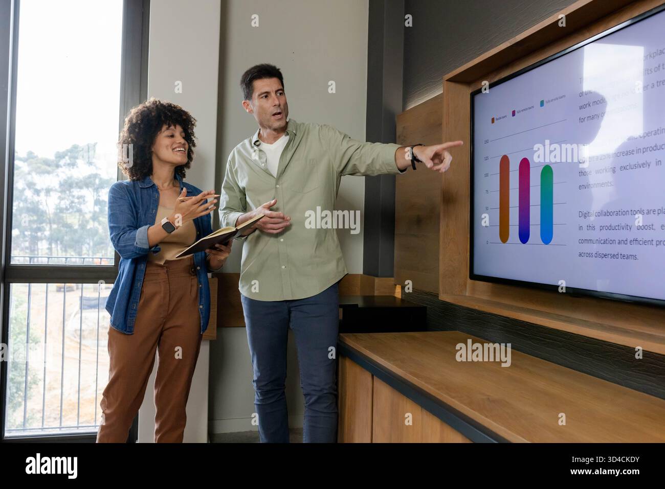Présentation d'un graphique à barres sur l'écran mural, réunion de plusieurs collègues au bureau, avec ordinateur portable et stylo Banque D'Images