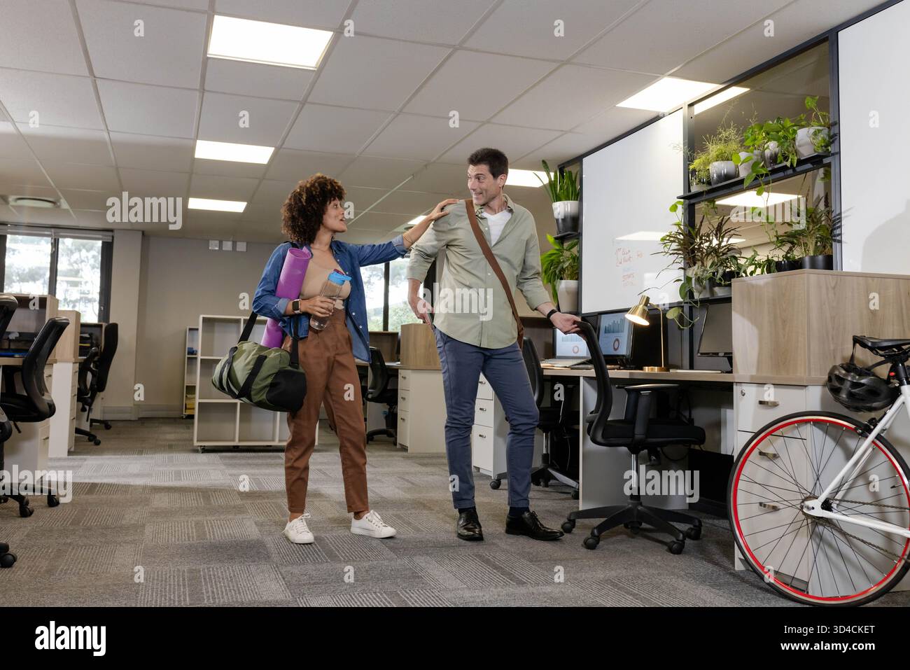 Divers collègues marchant dans un bureau ouvert, portant tapis de yoga, sac de sport et sac messager Banque D'Images