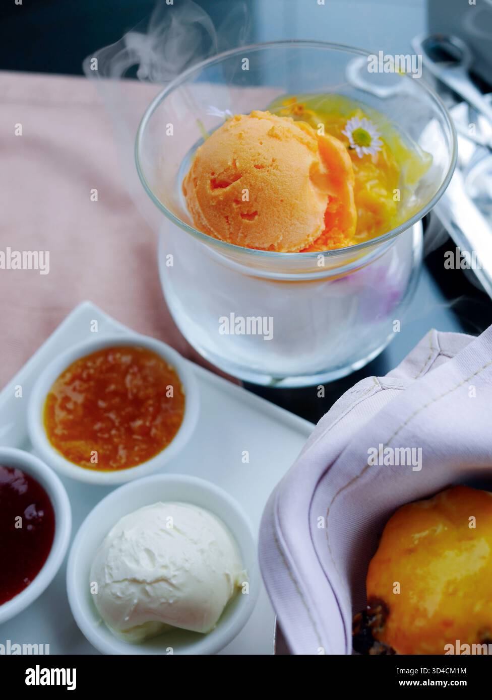 Sorbet orange vibrant servi dans un bol en verre frais avec un effet de fumée subtil, style de nourriture moderne et lumineux idéal pour les menus de café, promotions de desserts, Banque D'Images