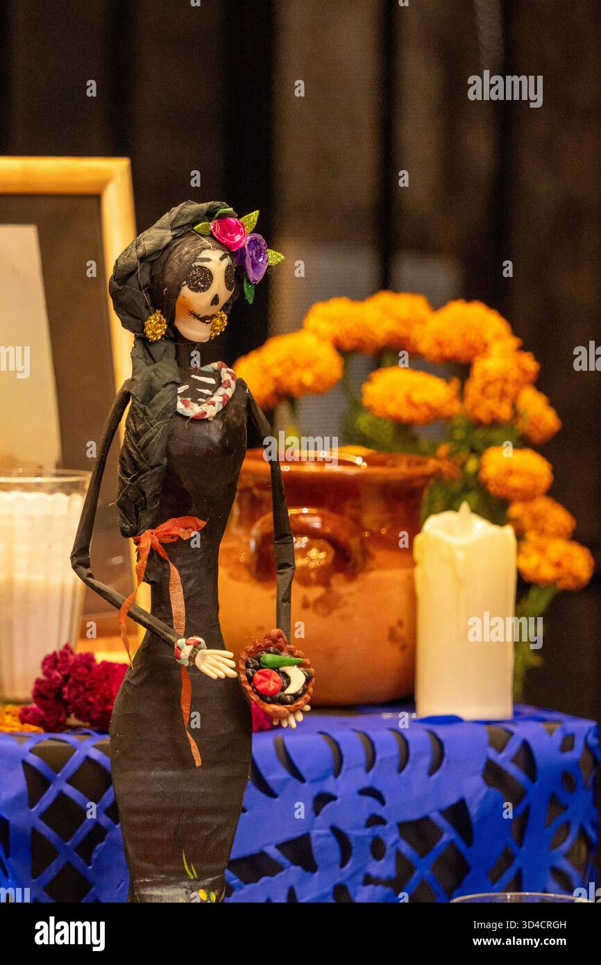 Une femme squelette tient un panier de fruits et est entourée de fleurs oranges. Fête mexicaine de la tradition des morts, offrandes, nourriture, couleurs, décoration Banque D'Images
