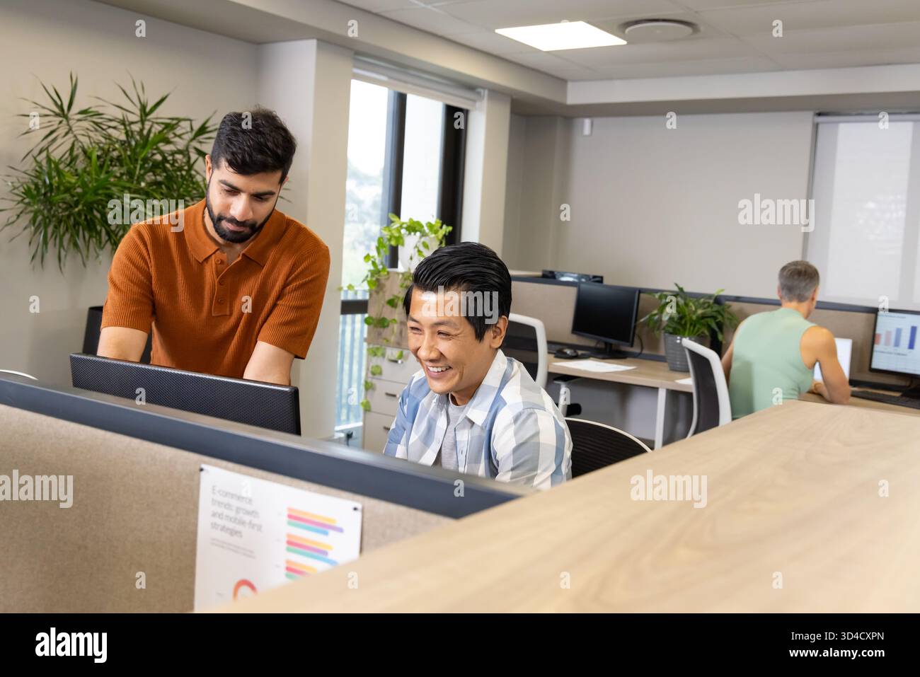 Collaboration de divers collègues masculins éditant des documents dans un bureau ouvert, avec deux moniteurs Banque D'Images