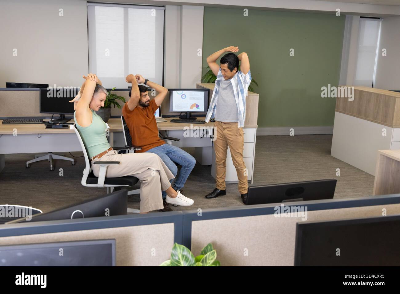 Étirer divers collègues prendre une pause rapide dans un bureau ouvert, avec des moniteurs et des usines Banque D'Images