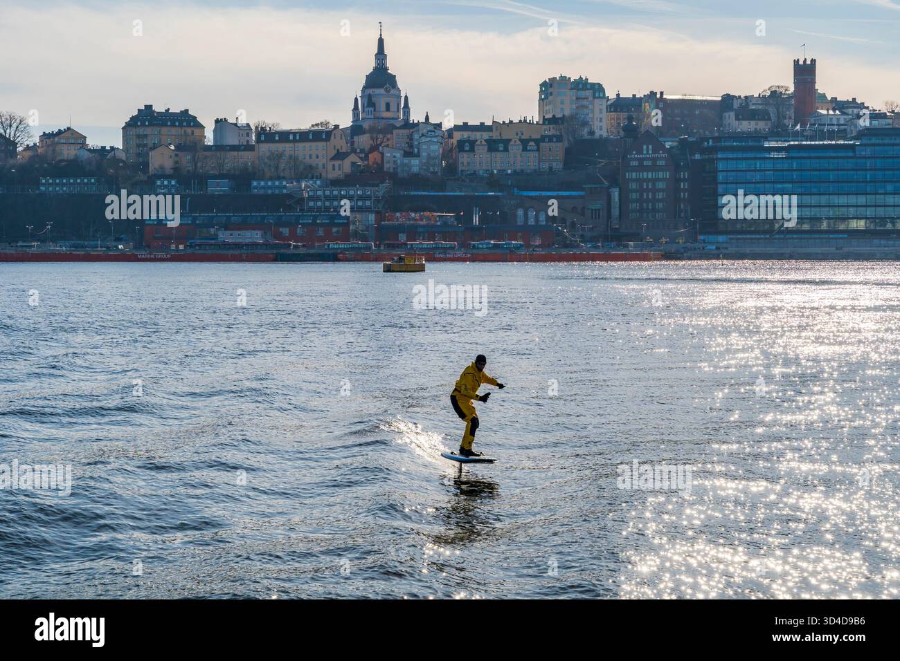 SUÈDE, STOCKHOLM - 08 MARS 2025 : un homme monte une planche d'hydroptère électrique sur un canal du port de Stockholm. Les hydroptères électriques offrent une glisse A. Banque D'Images