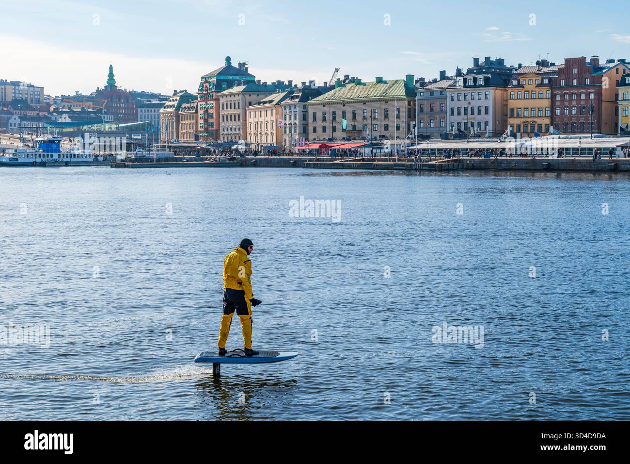 SUÈDE, STOCKHOLM - 08 MARS 2025 : un homme monte une planche d'hydroptère électrique sur un canal du port de Stockholm. Les hydroptères électriques offrent une glisse A. Banque D'Images