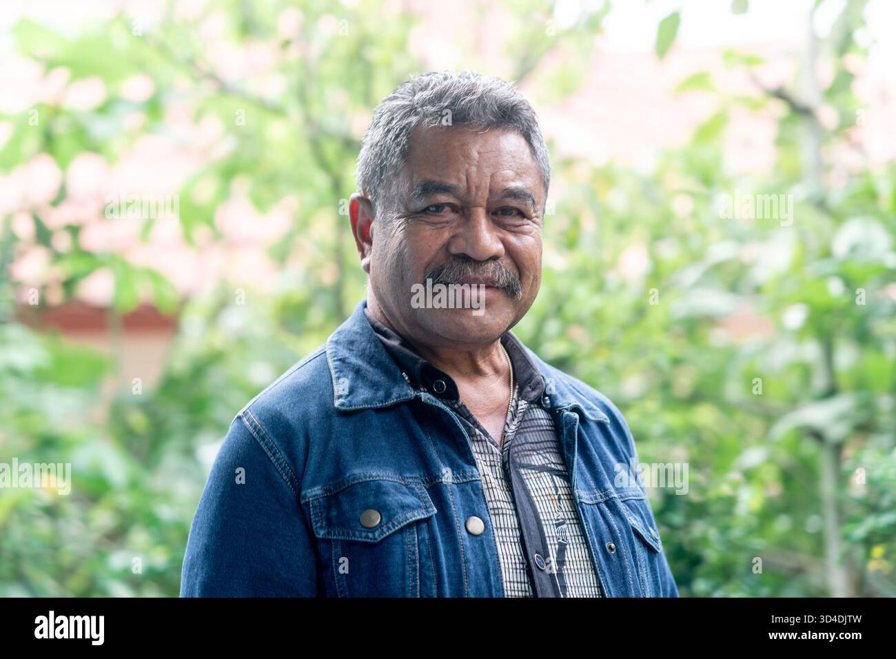Un portrait chaleureux et amical d'un homme asiatique senior heureux souriant à la caméra. Porter une veste en denim. Banque D'Images