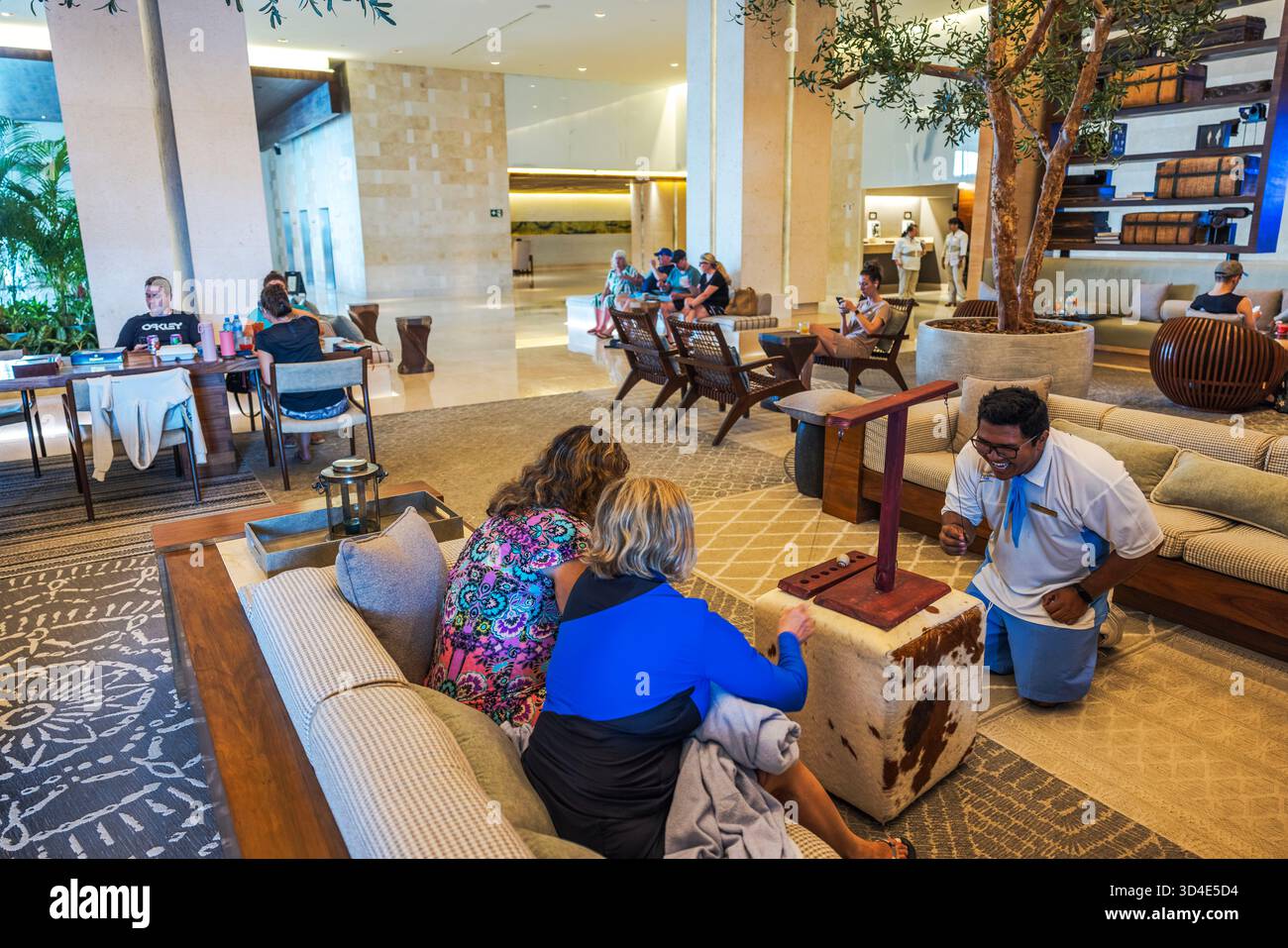 Les clients de l'hôtel jouent à un jeu de lancer d'anneau avec un membre du personnel dans le hall spacieux et moderne au design intérieur confortable. Mexique. Cancun. Banque D'Images