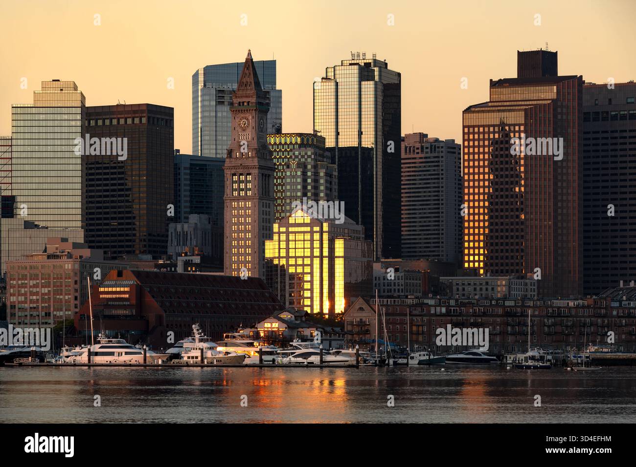 Les gratte-ciel du centre-ville de Boston au lever du soleil, vus de l'autre côté de l'eau depuis East Boston, mettant en valeur la tour de l'horloge. Banque D'Images