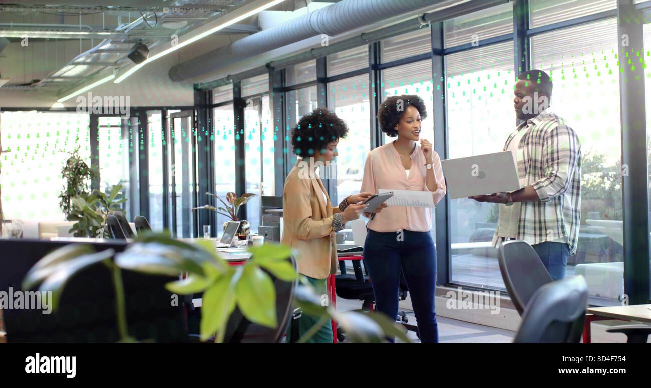 Discuter avec des collègues en tenue professionnelle partageant ordinateur portable, tablette et documents dans un bureau moderne Banque D'Images