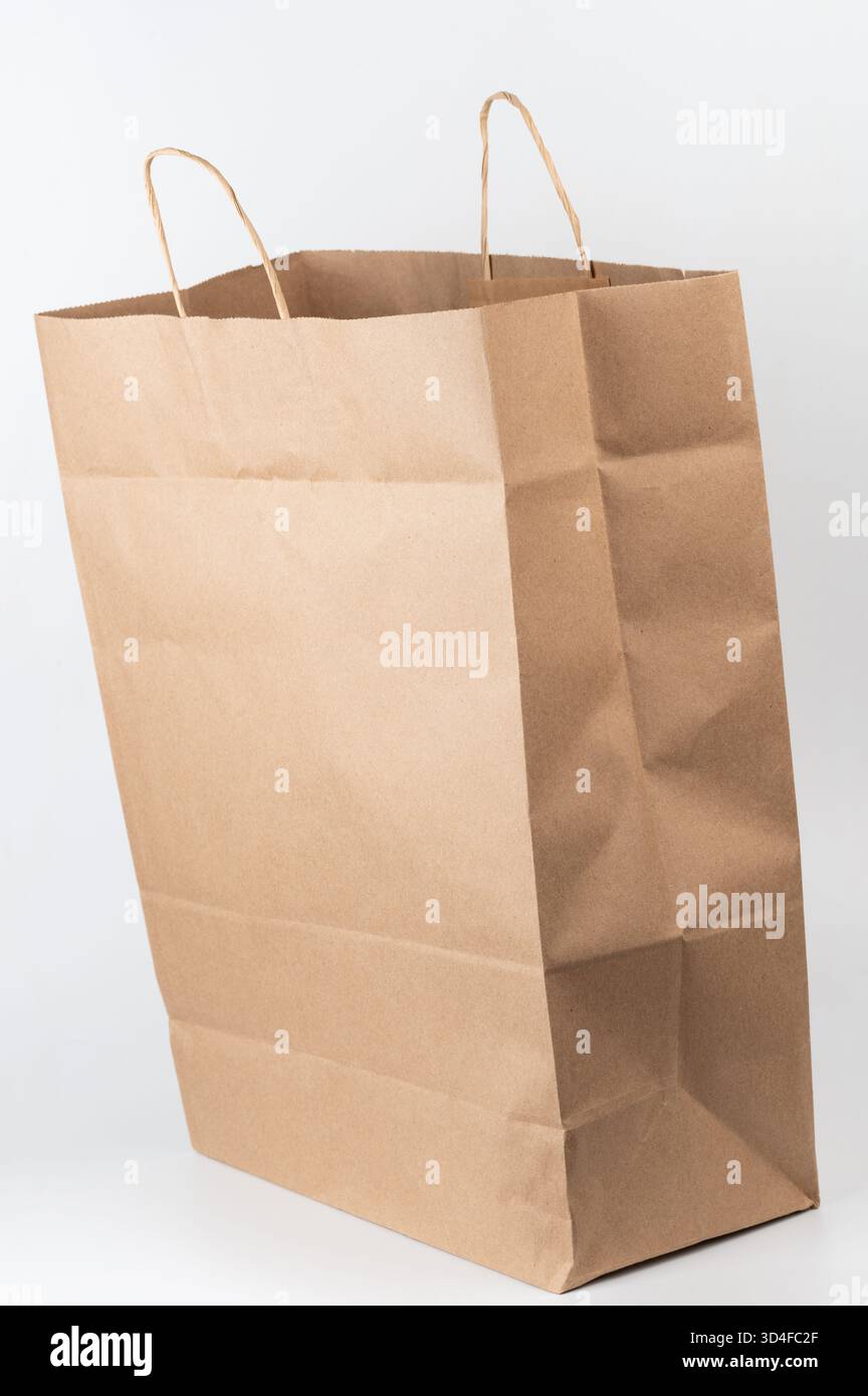 Sac en papier brun se tient debout sur fond blanc, parfait pour faire du shopping ou emballer des cadeaux avec son design robuste. Banque D'Images