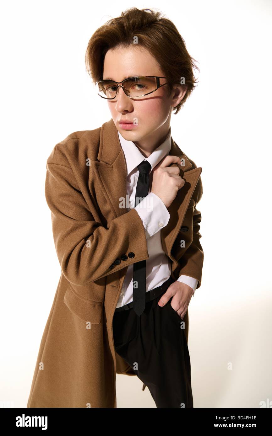 Confiant jeune homme modèle des vêtements élégants, mélangeant l'élégance avec une touche moderne dans le studio. Banque D'Images