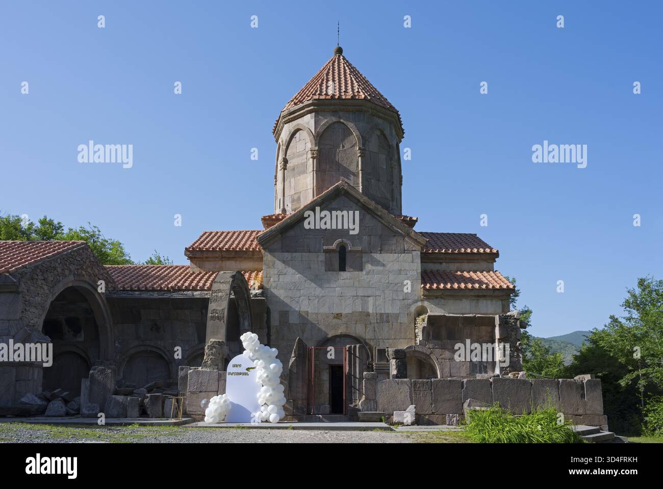 Église historique avec toit de tuiles et ciel bleu en arrière-plan entouré de verdure, monastère de Wahanavank, province de Syunik, Syunik, Arménie Banque D'Images
