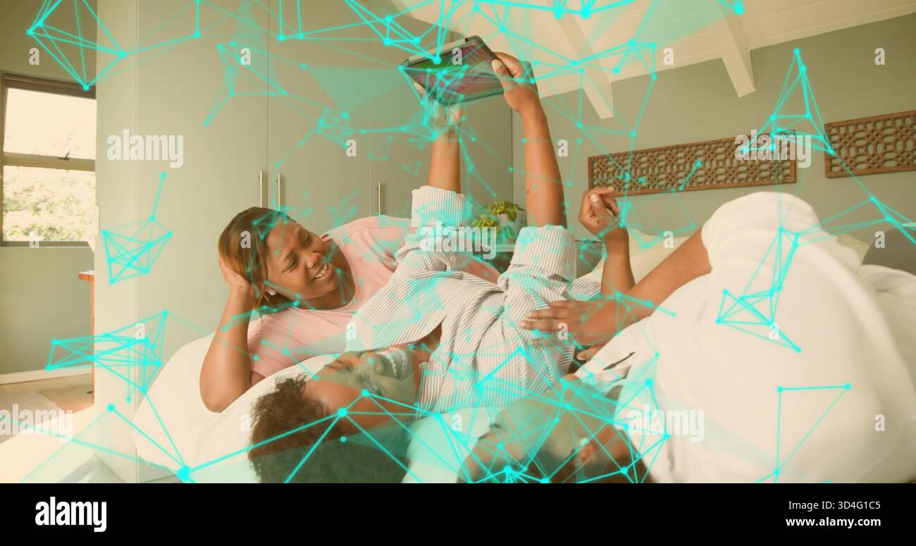 Couché trois femmes noires dans des vêtements de détente sur le lit dans une chambre lumineuse, tenant smartphone, recouvrement sarcelle Banque D'Images