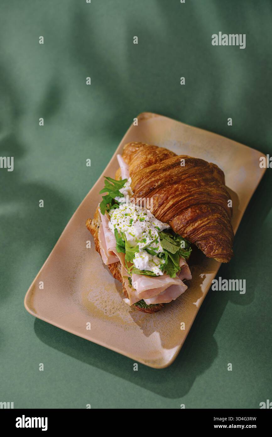 Nourriture, sandwich croissants frais avec jambon, fromage et légumes verts, servi sur une assiette élégante Banque D'Images