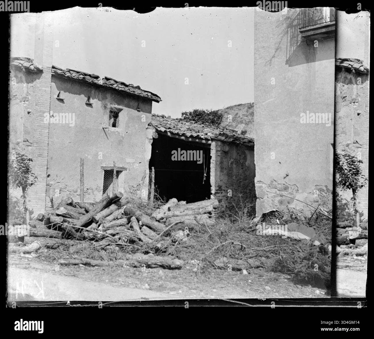 La façade d'une maison en ruines avec une pile de bûches devant, photographiée par Antoni Bartumeus i Casanovas entre 1897 et 1925. L'image capture l'état délabré de la structure et de l'environnement environnant. Banque D'Images