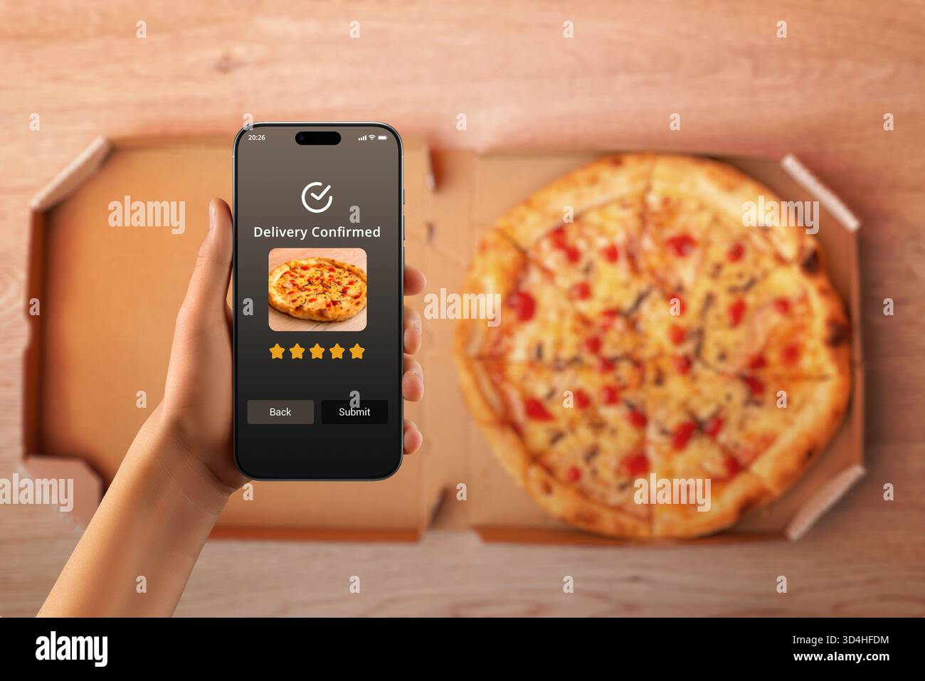 Main tenant smartphone avec application de livraison confirmant la commande de pizza au-dessus de la boîte ouverte, concept de service de restauration en ligne et livraison rapide Banque D'Images