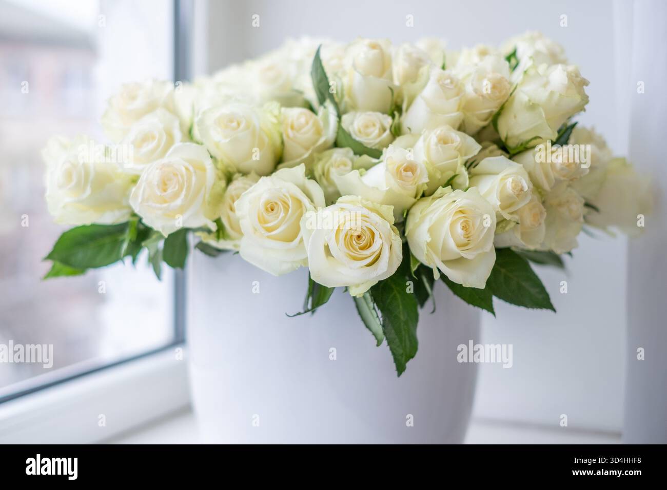 Un superbe arrangement de roses blanches dans un vase décoratif, parfait pour mettre en valeur les célébrations et les anniversaires, ajoutant une touche d'élégance et de beauté Banque D'Images