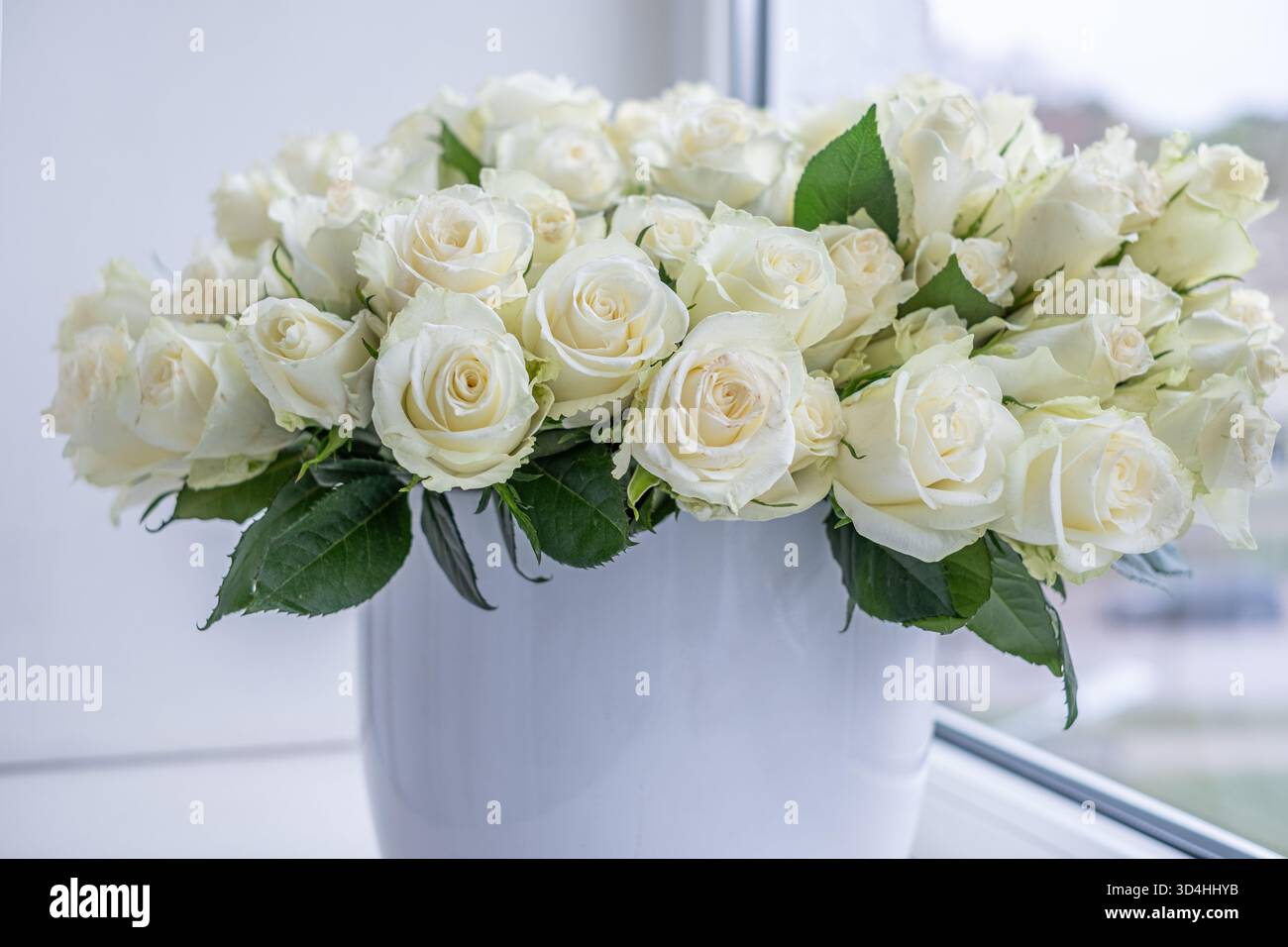 Un superbe arrangement de roses blanches dans un vase élégant, parfait pour mettre en valeur les célébrations et les anniversaires, ajoutant une touche d'élégance à n'importe quel cadre Banque D'Images