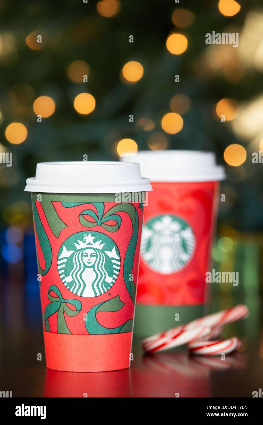 Dallas, Texas - 9 novembre 2025 : café Starbucks dans les nouvelles tasses des fêtes conçues pour 2025. Affiché avec des cannes de bonbons sur la table en bois. Bokeh des fêtes Banque D'Images