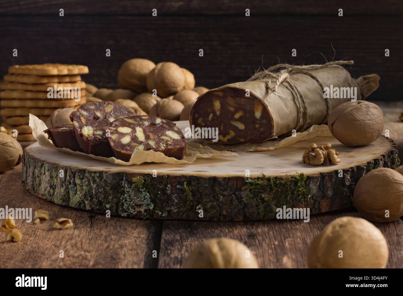 Un délicieux salami au chocolat est assis sur une planche de bois, tranché pour révéler son intérieur rempli de noix. Banque D'Images