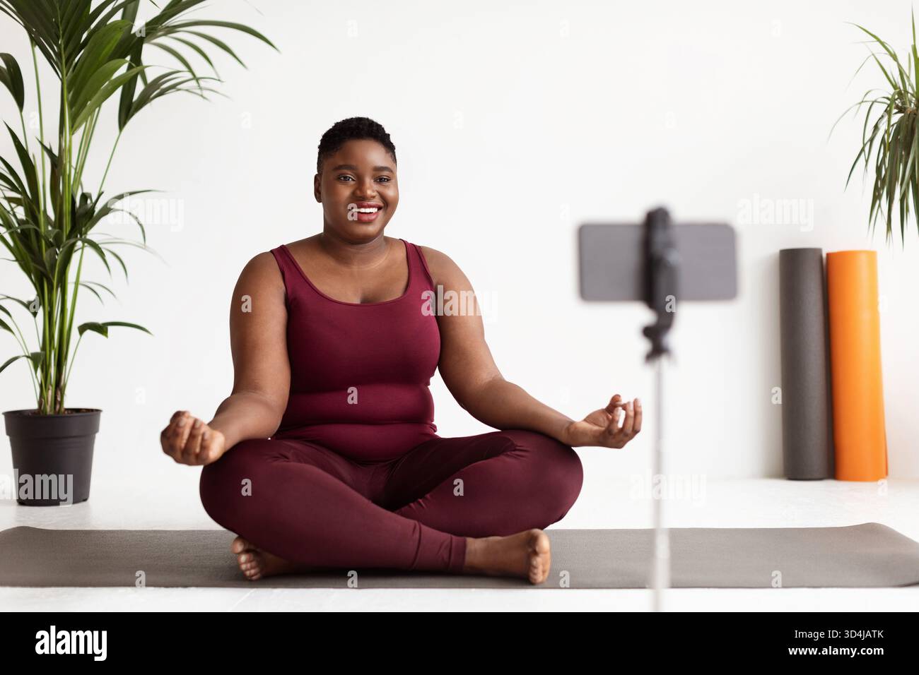 Joyeuse femme de taille plus profite de cours de yoga en ligne à la maison dans la tenue de fitness Banque D'Images