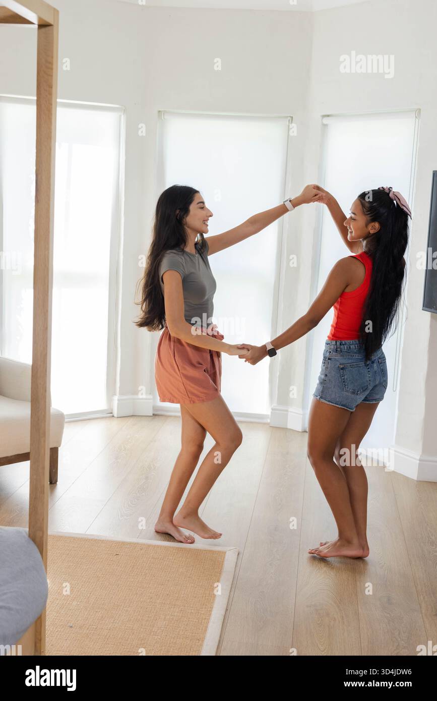 Filer diverses amies féminines tenant les mains pieds nus dans la chambre à coucher, avec espace de copie de tapis beige Banque D'Images
