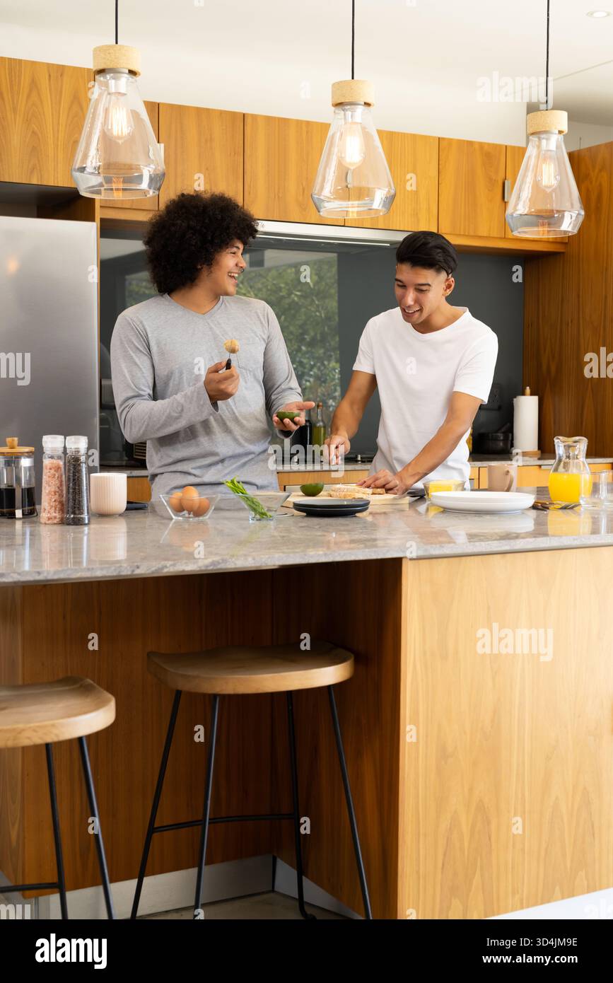 Hacher avocat divers amis masculins préparant le petit déjeuner dans une cuisine moderne, avec îlot de marbre Banque D'Images