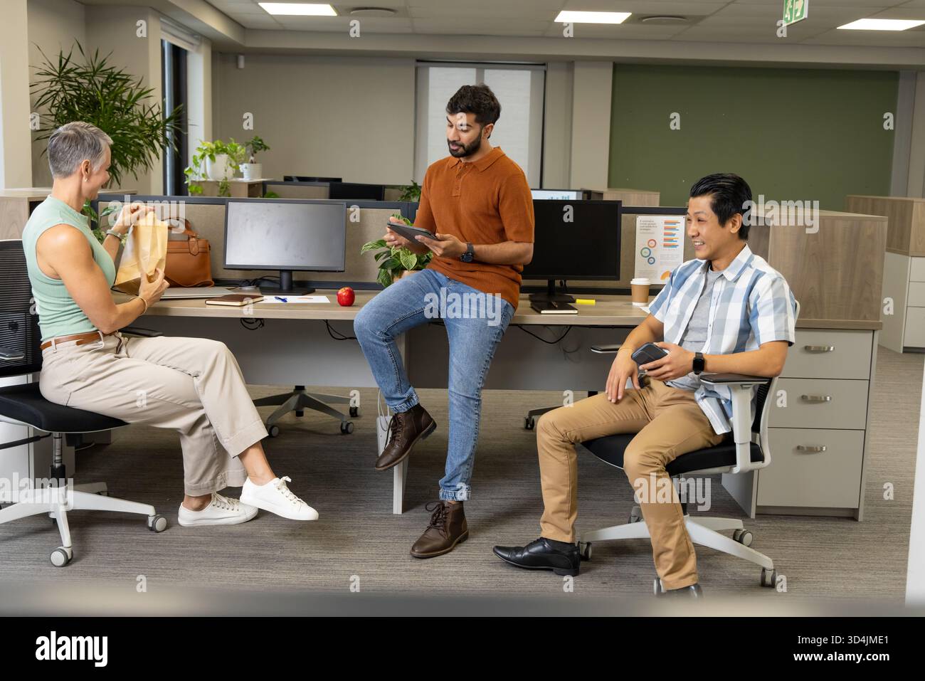 Collaborer avec divers collègues déballer le sac à lunch et tapoter la tablette avec le café au bureau Banque D'Images