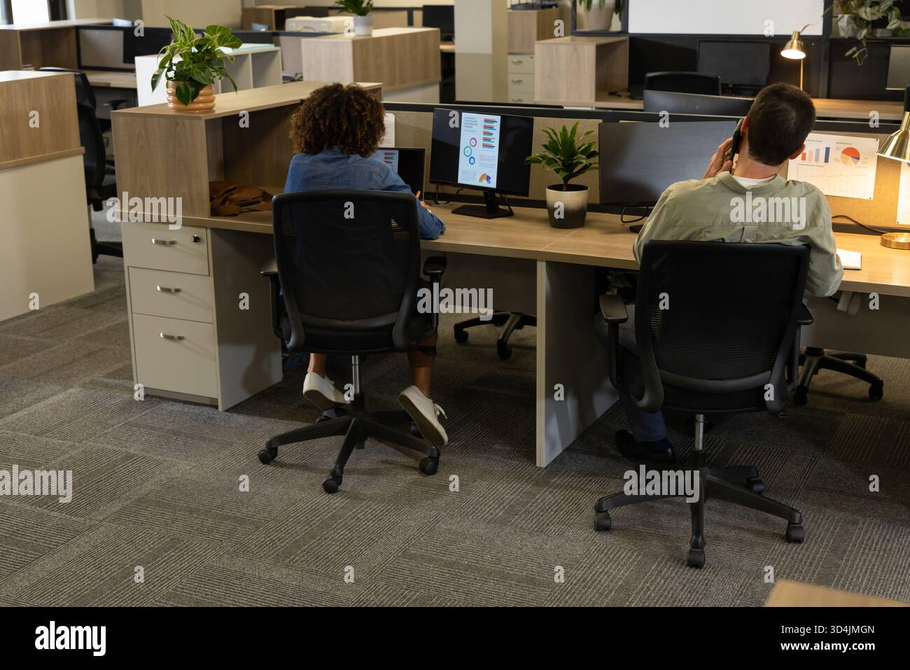 Travailler divers collègues tapant sur des bureaux en bois dans un bureau ouvert, avec deux moniteurs Banque D'Images