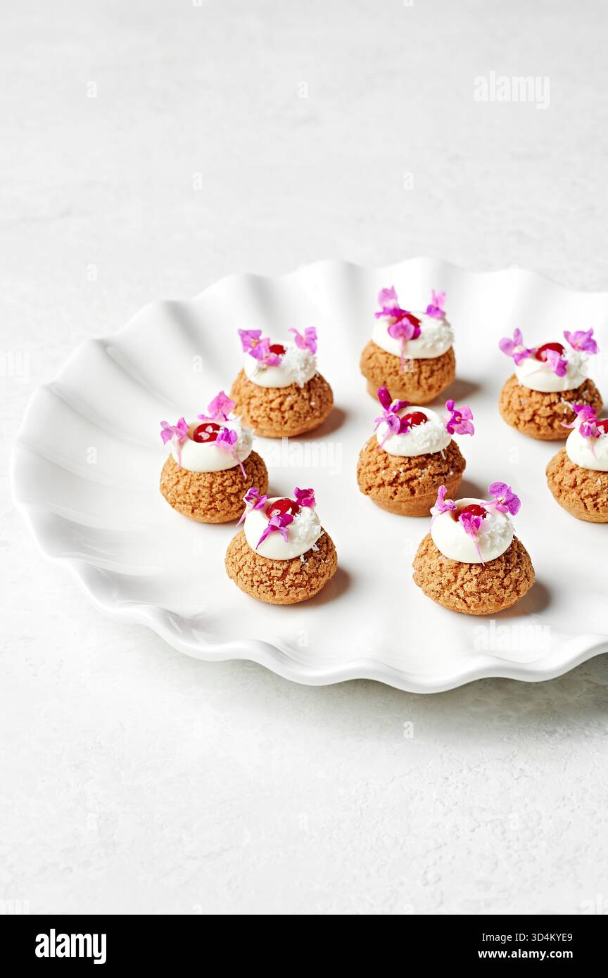 Assiette de brioches à choux à la framboise et à la noix de coco avec du lait caillé de framboise, de la crème de coco et une saupoudrée de noix de coco Banque D'Images