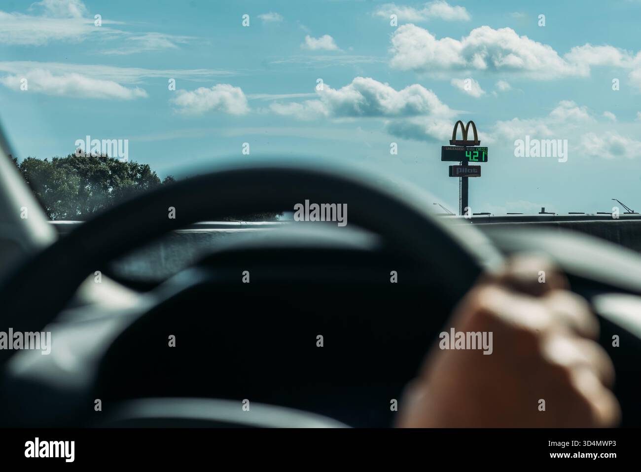 POV d'une personne tenant le volant conduisant à côté d'une arche dorée McDonald's et d'une station-service en Floride, États-Unis Banque D'Images