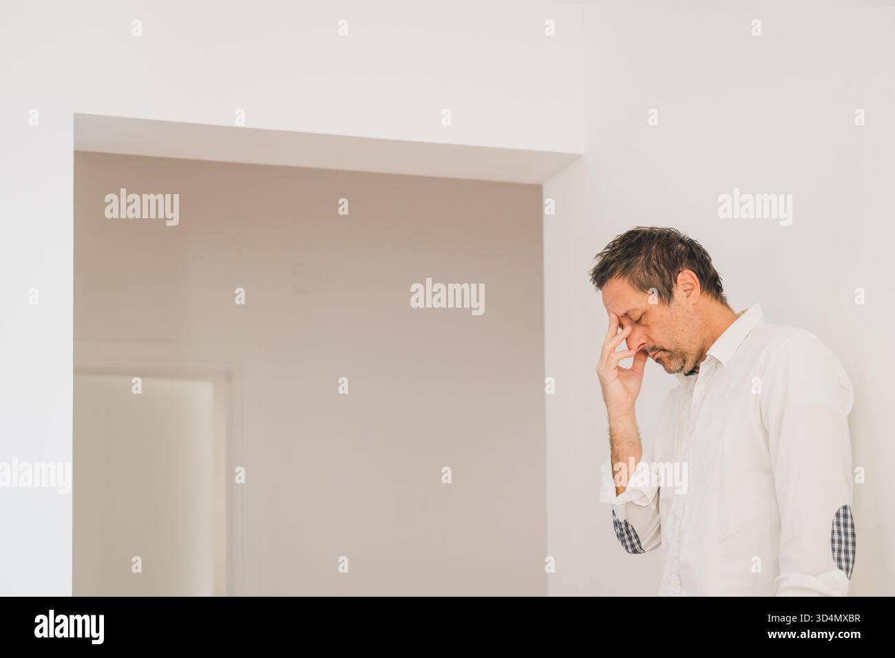 Homme mature stressé touchant le front dans la frustration tout en se tenant à l'intérieur. Mise au point sélective. Banque D'Images
