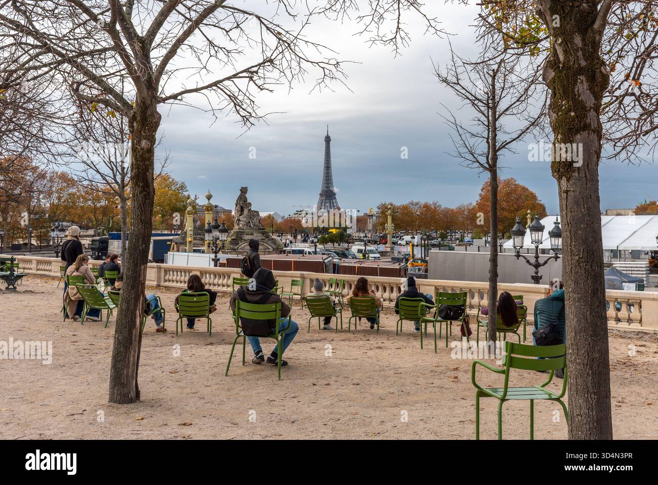 Paris, France, 11.10.2025. Les gens assis dans le jardin des Tuileries sur des chaises de jardin vertes regardant vers la Tour Eiffel par un jour nuageux d'automne. Banque D'Images