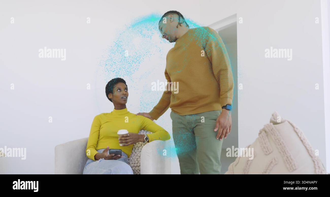 Femme assise en haut jaune, homme debout en pull moutarde penché dans le salon, tenant le téléphone Banque D'Images