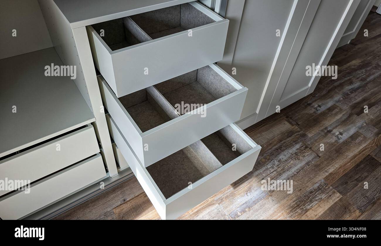 Ouvrez les tiroirs avec des organisateurs gris intégrés dans une armoire blanche. Tri et organisation Banque D'Images