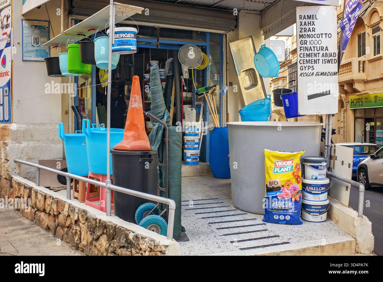 Sliema, Malte - 2025 : seaux colorés, articles ménagers, outils, peintures et ciment exposés à l'extérieur d'une petite quincaillerie dans une rue de la ville maltaise. Banque D'Images