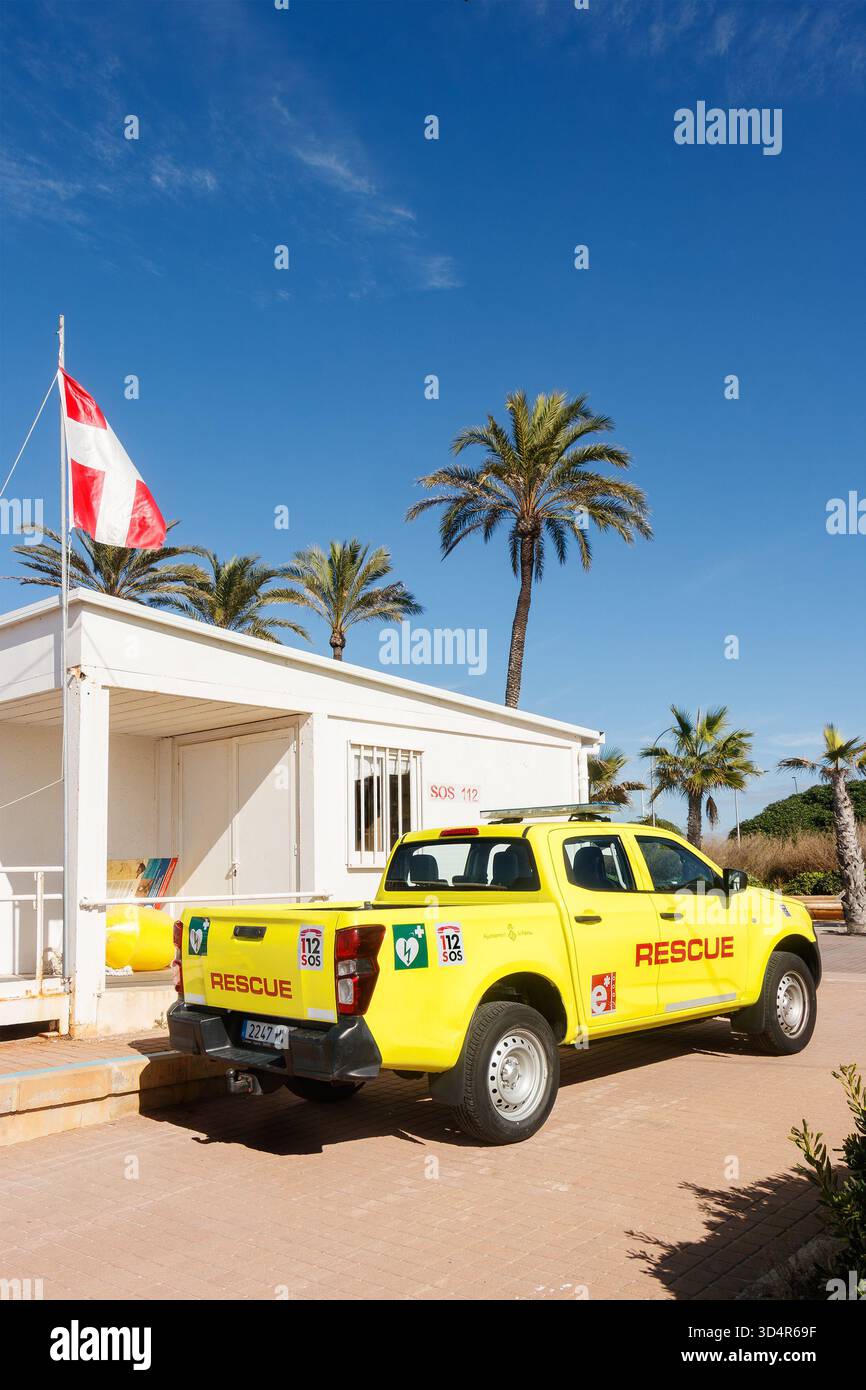 Pick-up de sauvetage jaune garé à côté d'une station de sauveteur de plage blanche avec un drapeau rouge et blanc et des palmiers en arrière-plan mallorca espagne Banque D'Images