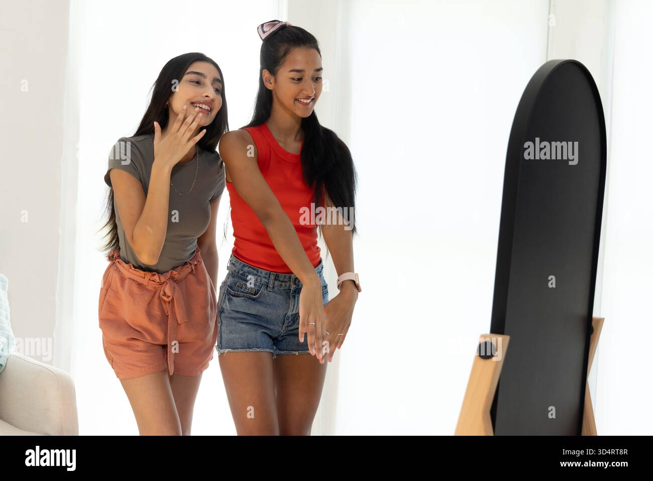 Souriant diverses amies féminines debout dans le salon moderne, avec miroir pleine longueur Banque D'Images