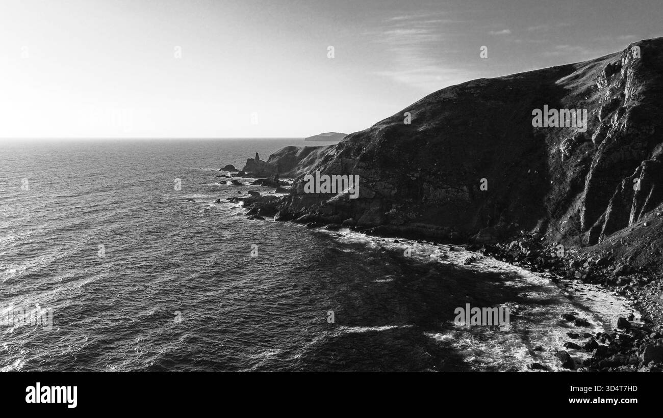 Vue aérienne en noir et blanc des falaises côtières accidentées avec des vagues le long du rivage Banque D'Images
