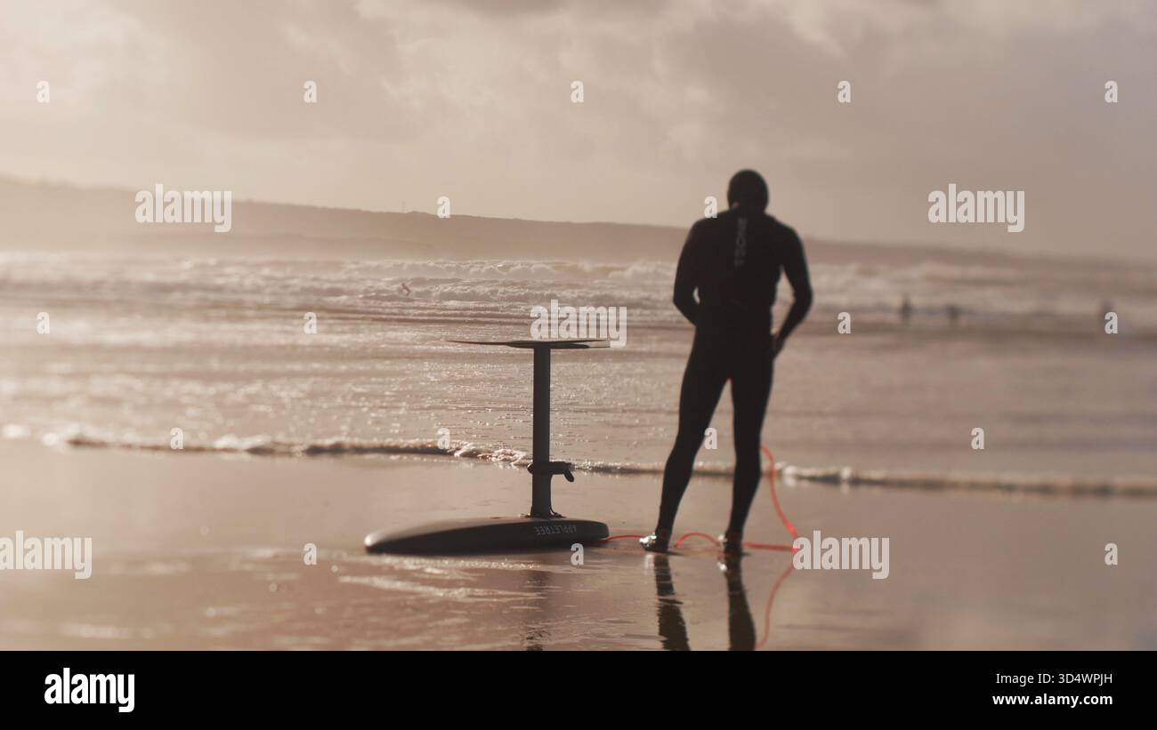 Un homme sur la plage se préparant à faire du surf de foiboard. Banque D'Images