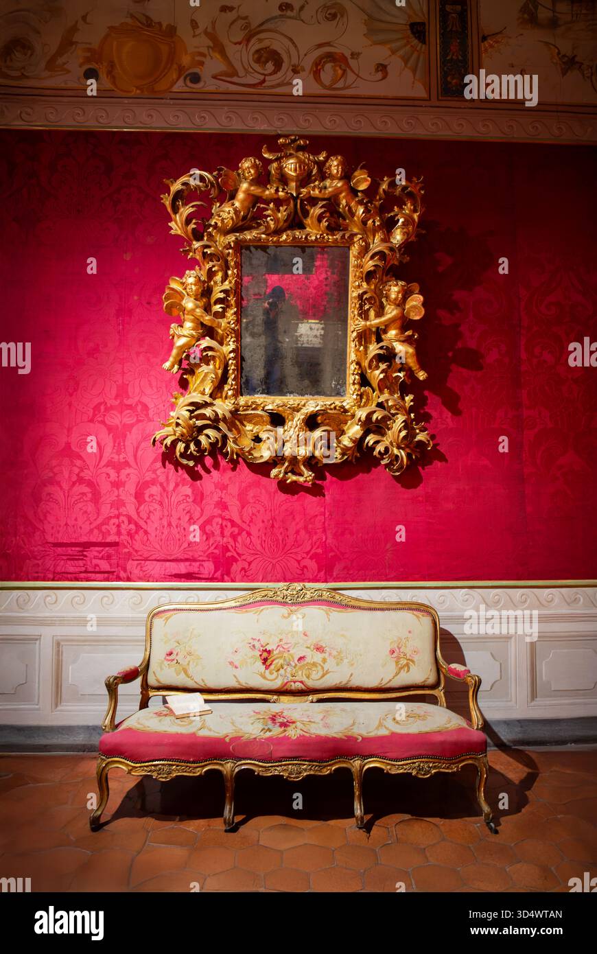Élégant intérieur baroque avec murs en velours rouge, cadres dorés et meubles anciens représentant le luxe royal européen. Banque D'Images